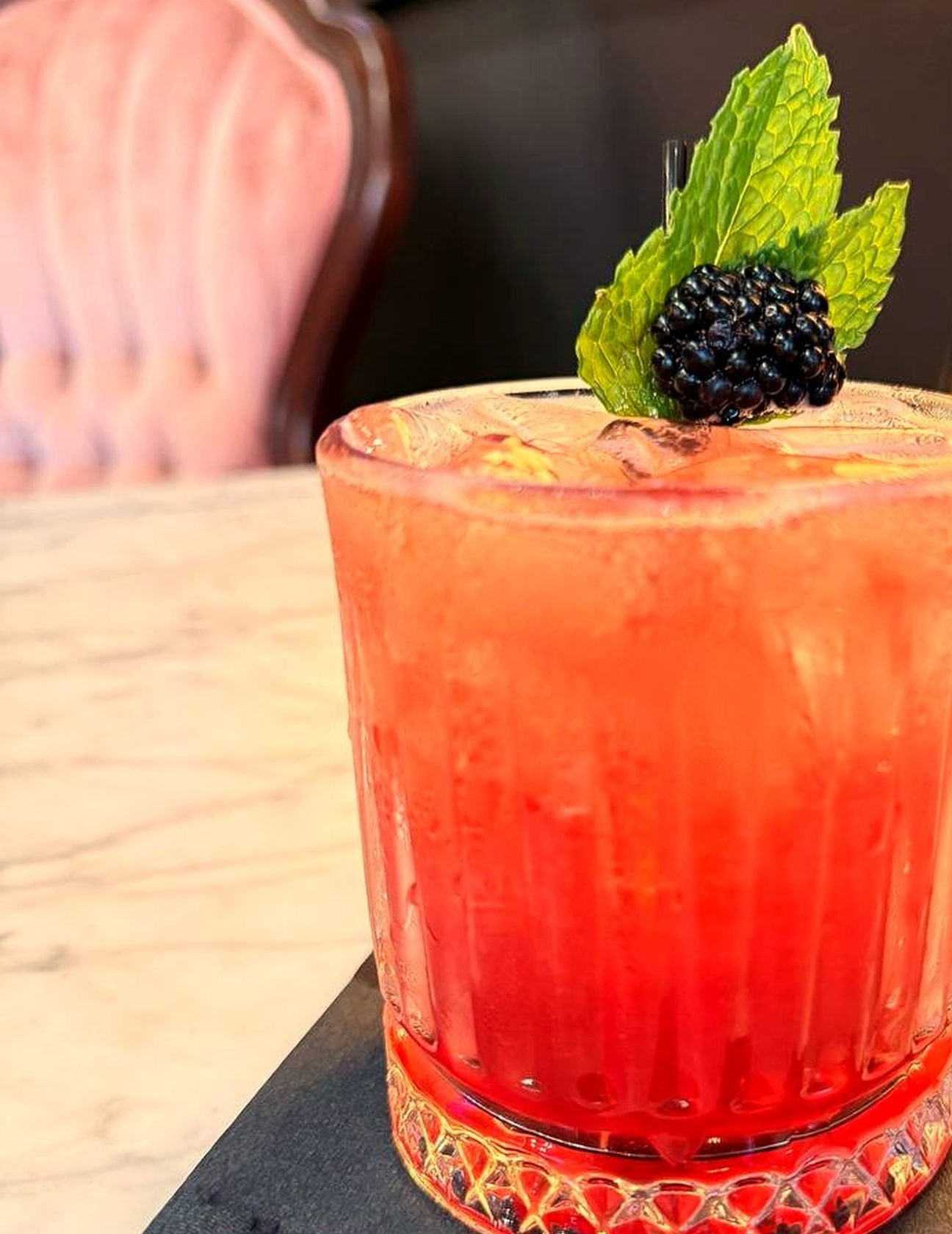 Close-up of a handcrafted cocktail with blackberry and mint garnish